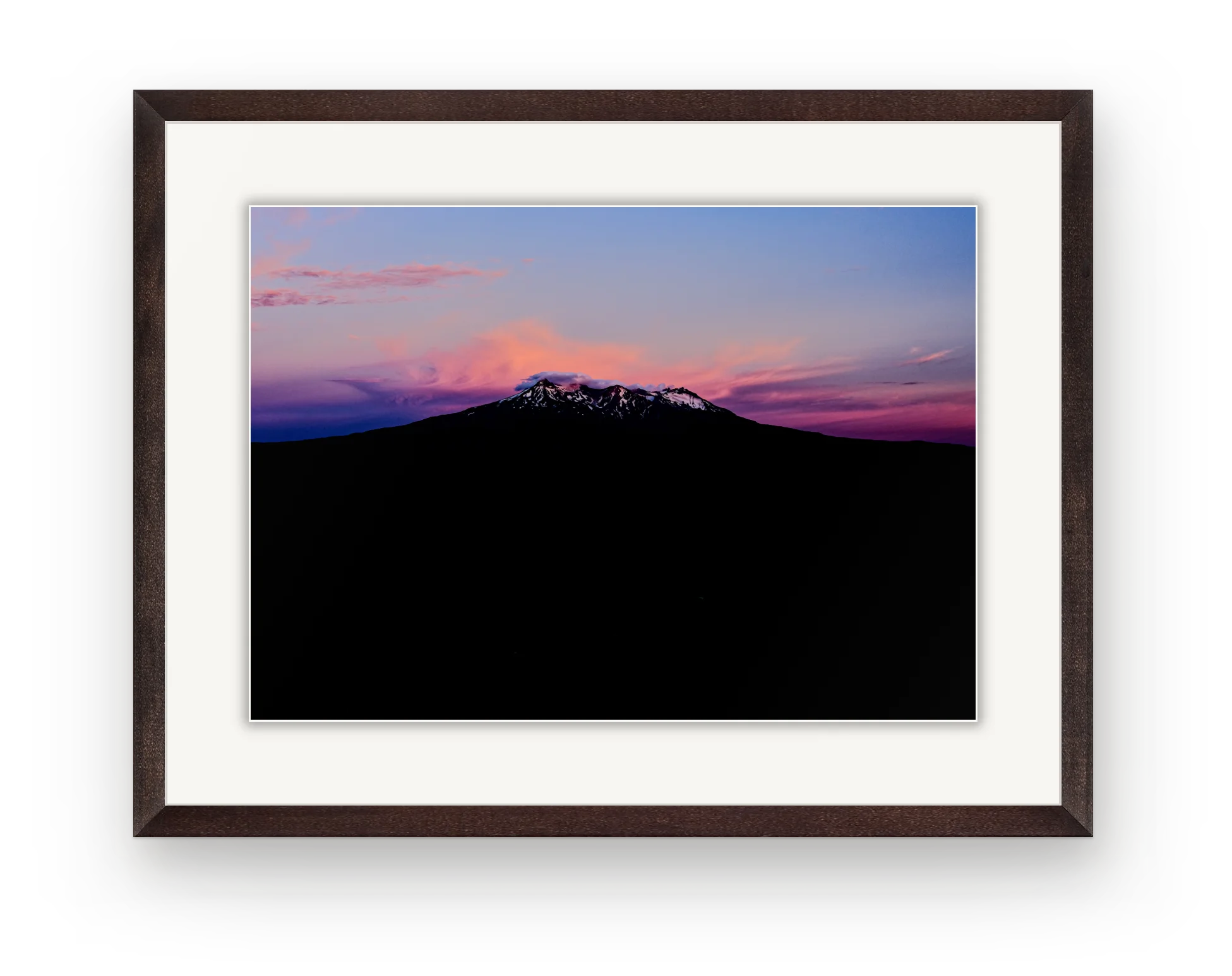 A pink sunset over Ruapehu in a dark walnut frame with a white mat.