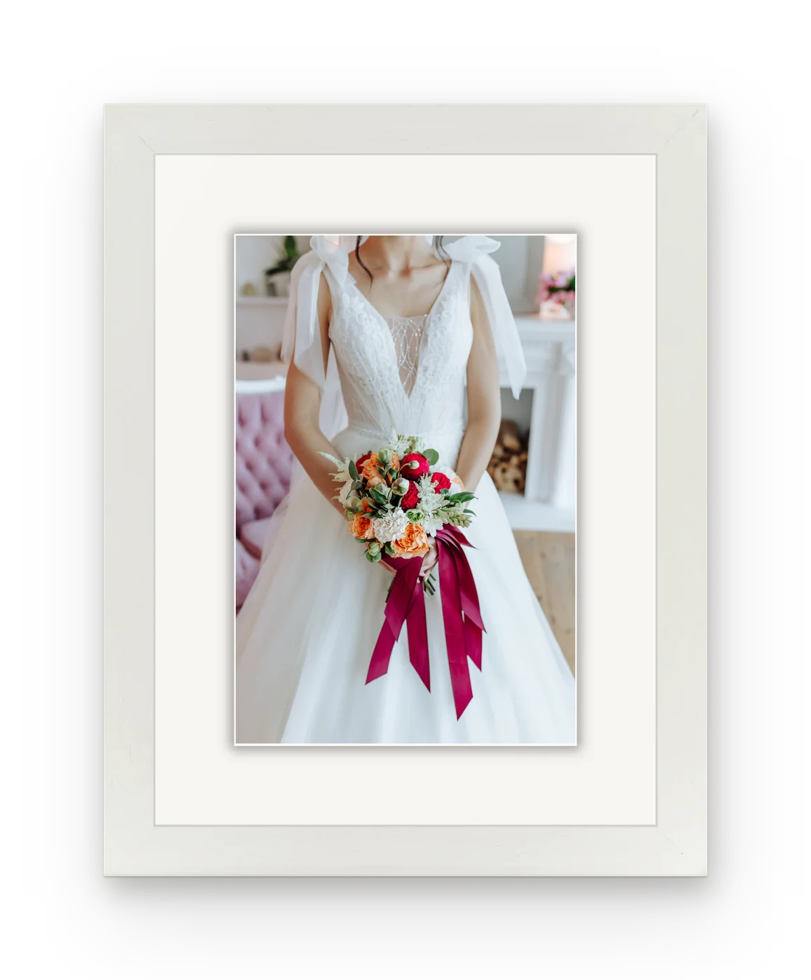 A bride holding a bouquet of red and orange roses, framed in white with a white mat.
